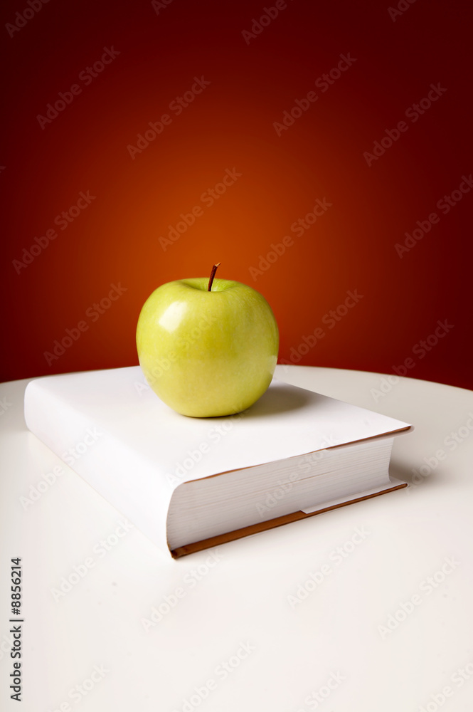 绿色闪亮的苹果躺在书上
