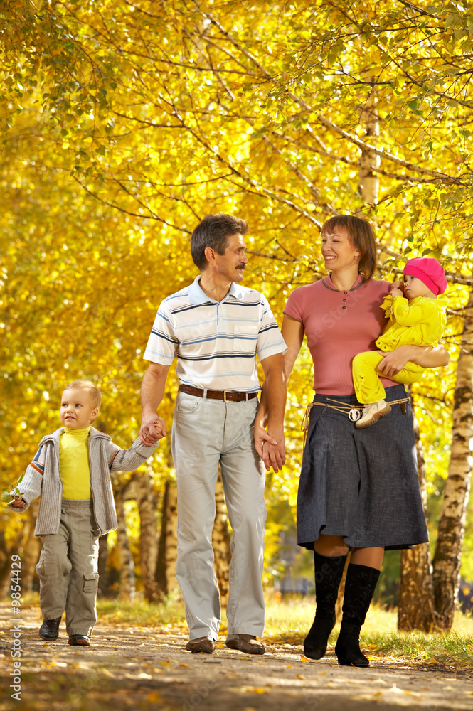 一家人带着两个孩子在秋天的公园散步