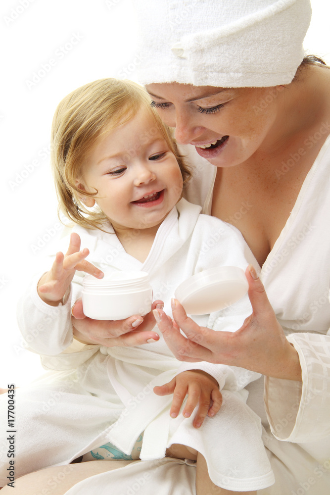 幸福的妈妈抱着婴儿的化妆品霜的照片