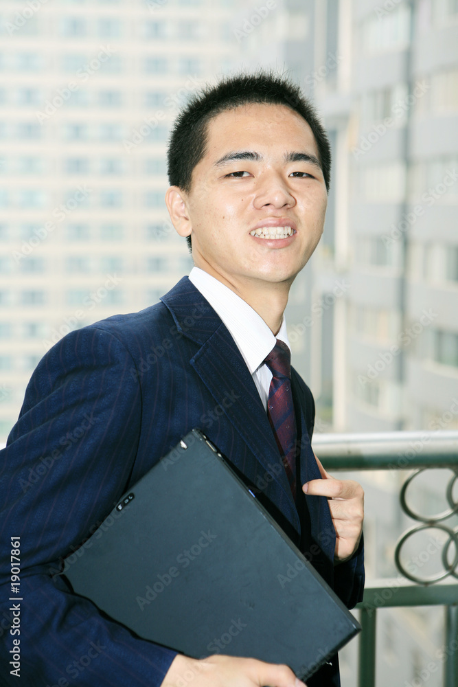 阳台上放着笔记本电脑的年轻亚洲商人