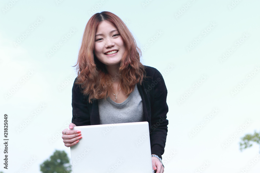 亚洲女孩与笔记本电脑户外