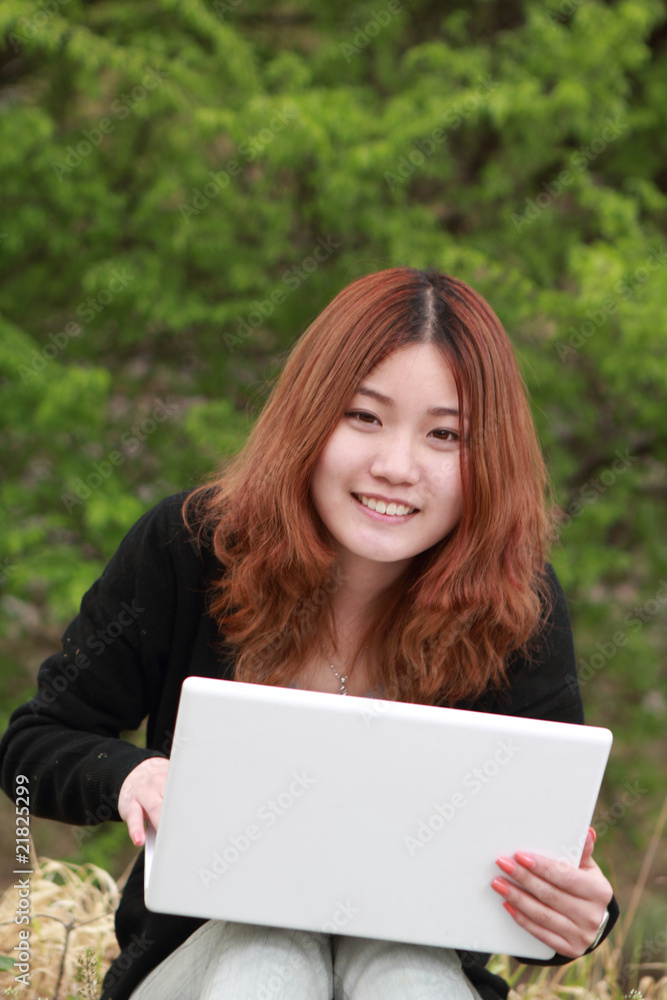 亚洲女孩与笔记本电脑户外