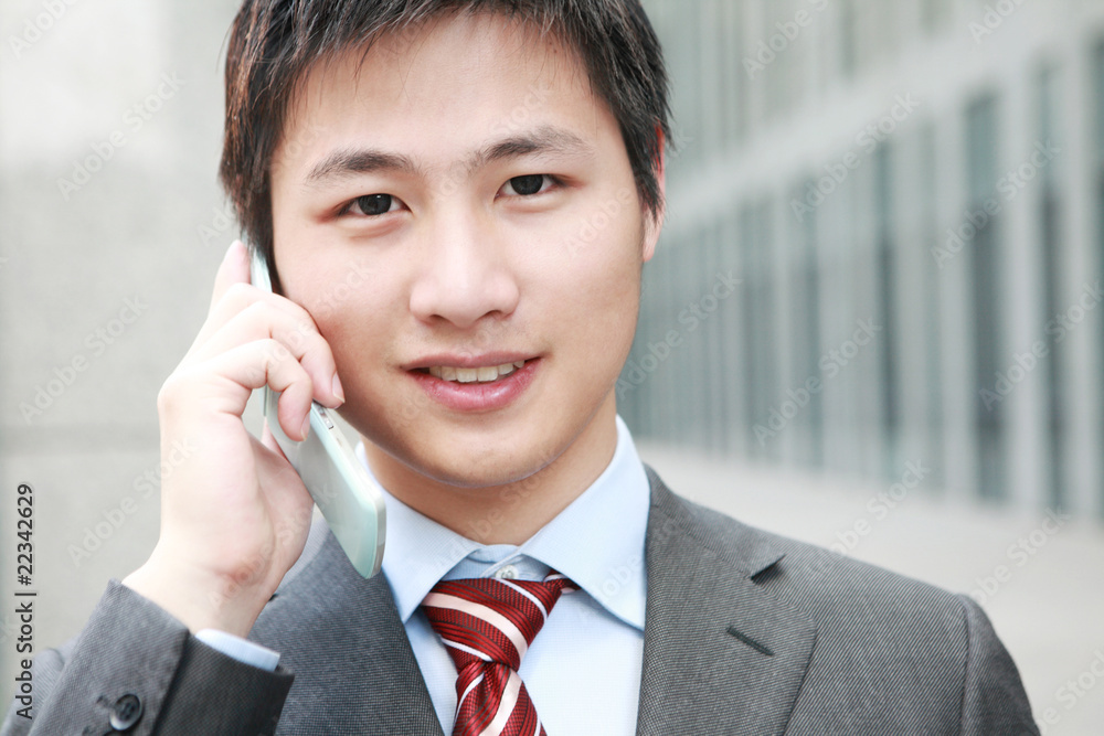 一个年轻的亚洲商人在户外接电话