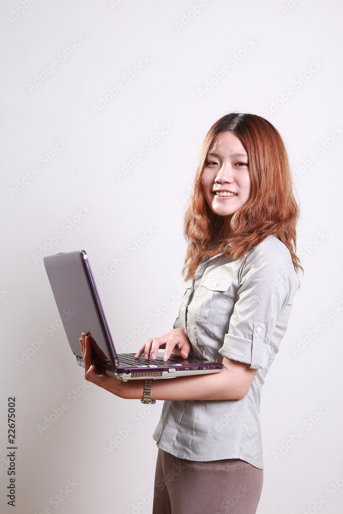 大笑的女人在白色背景下使用笔记本电脑。