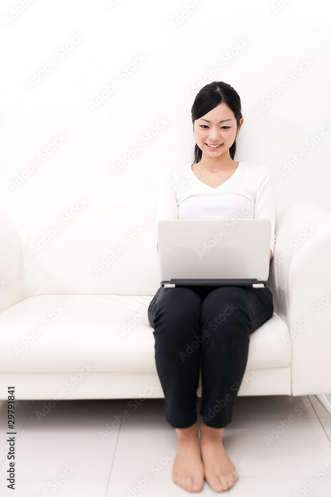 亚洲美女在沙发上用笔记本电脑