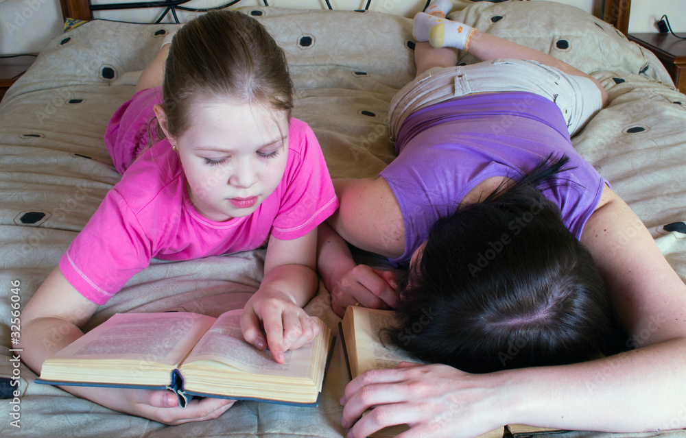 母亲和女儿在床上看书