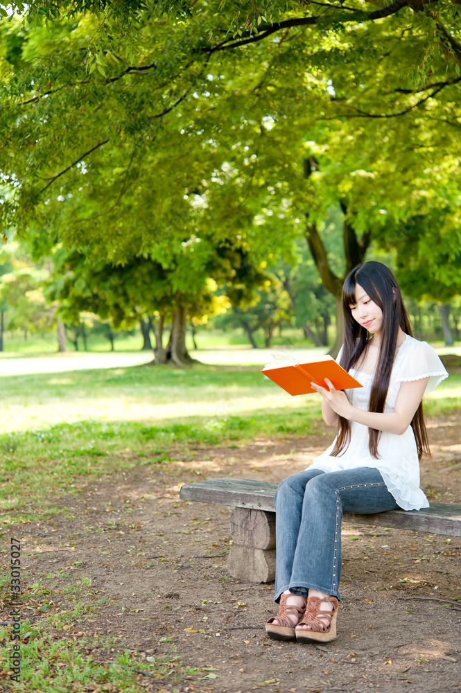 美丽的亚洲女人在公园看书