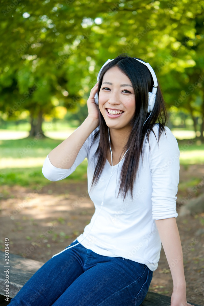 beautiful asian woman listening music in the park