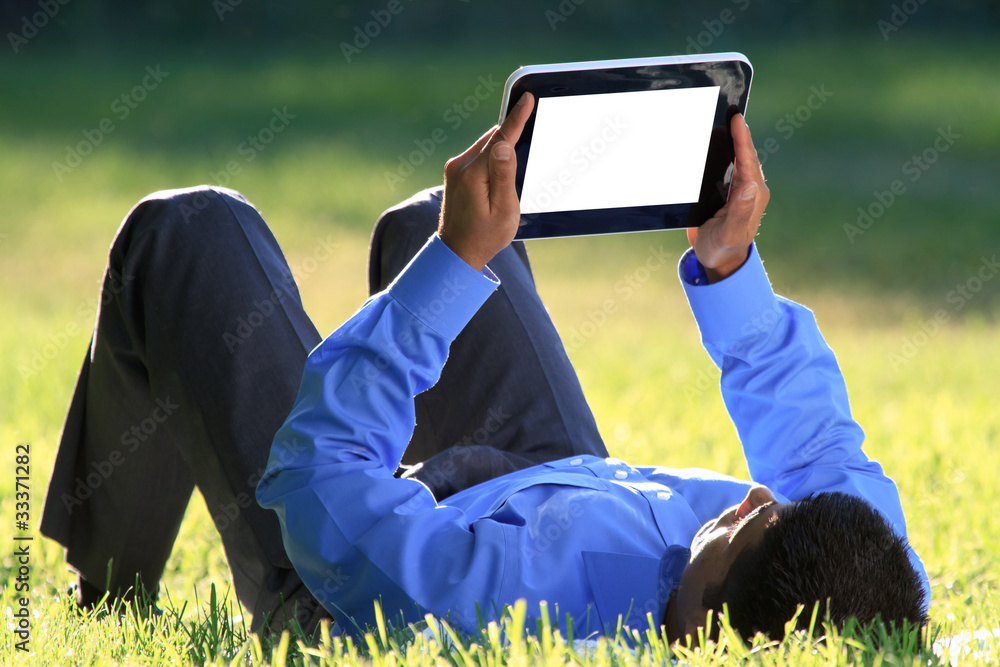 躺在草地上的数字平板电脑商人