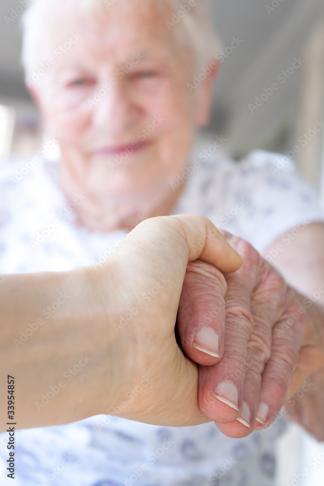 年轻的手牵着年长的女士的手