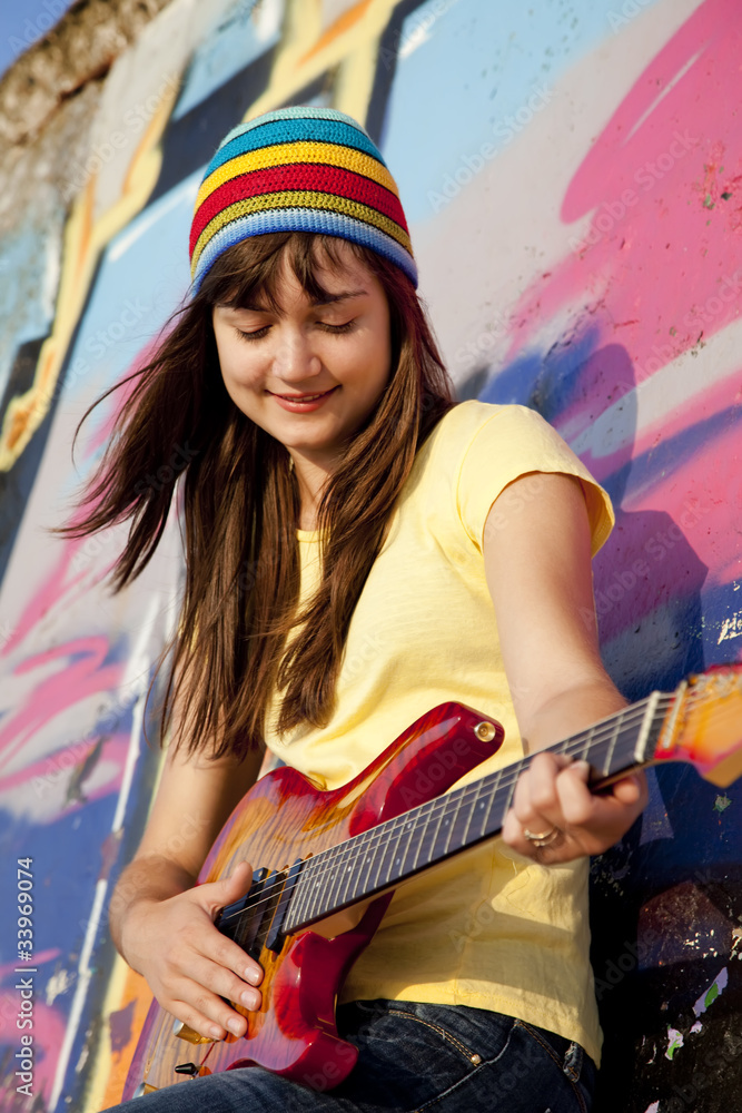 美丽的深色头发女孩，在backgro有吉他和涂鸦墙