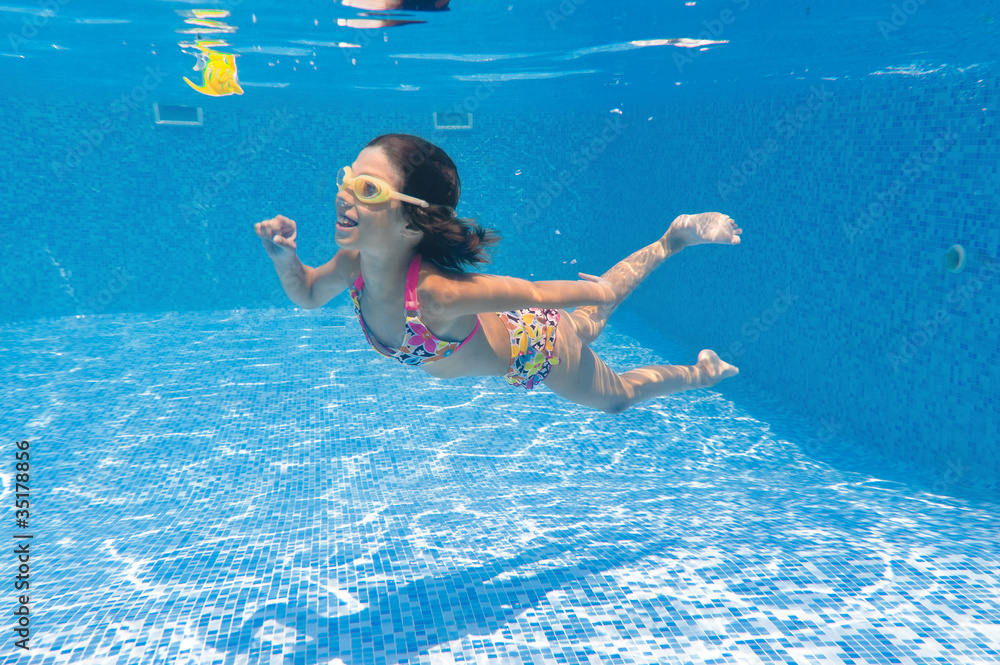 Happy smiling underwater kid playing in swimming pool