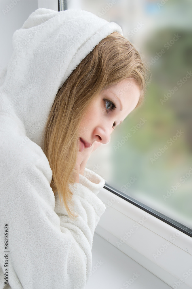 美丽的年轻女孩在窗前伤心