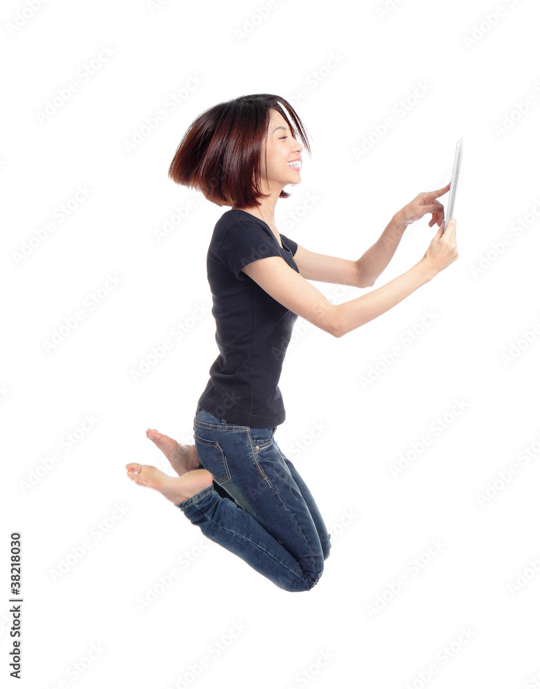 年轻美女快乐跳跃，在空中使用平板电脑