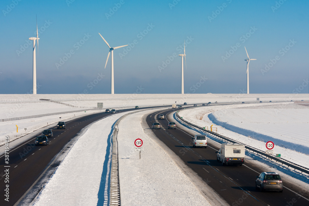 荷兰乡村冬季景观，配有高速公路和大型风力涡轮机