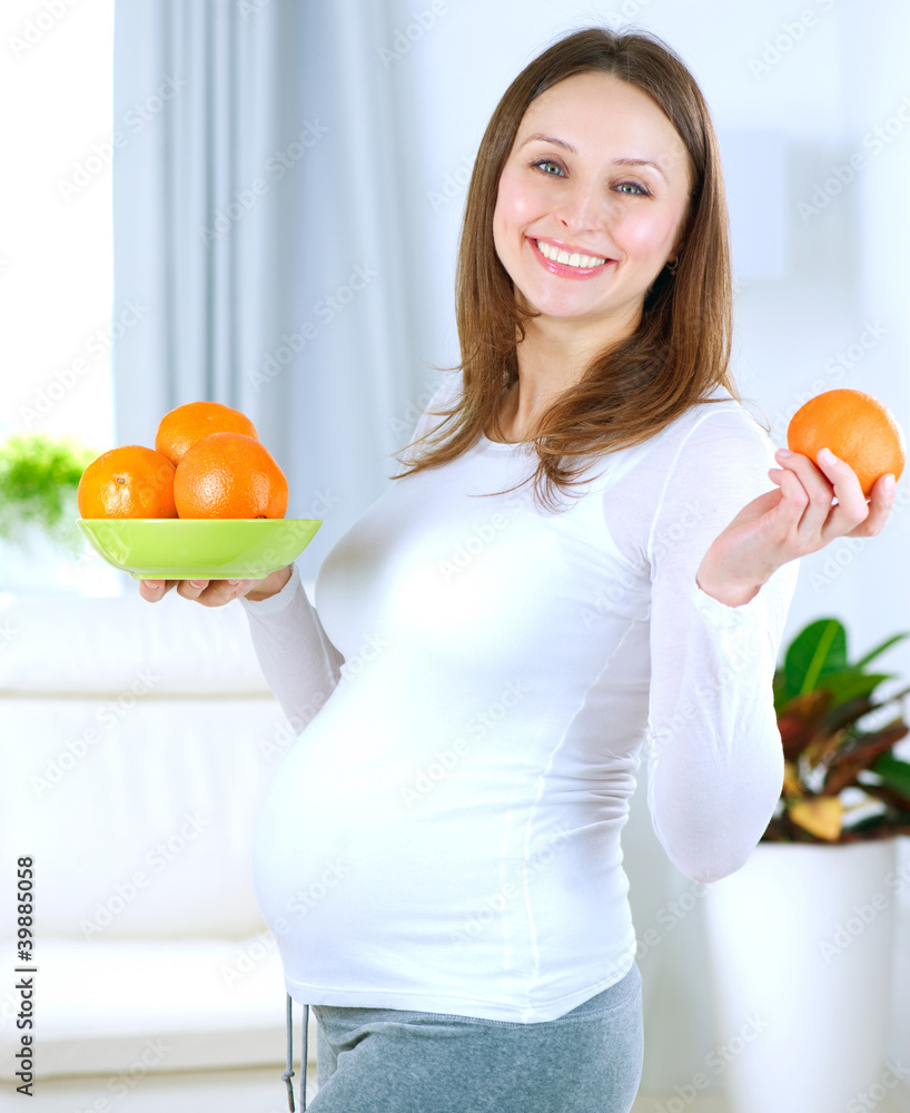 怀孕的年轻女人在家吃水果