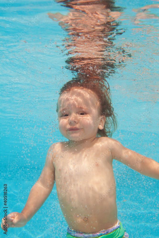 快乐的蹒跚学步的孩子在水下潜水