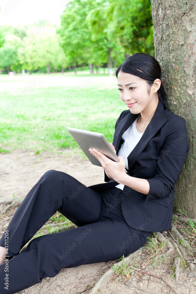 asian businesswoman using tablet in the park