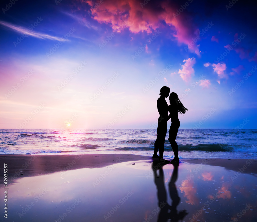 日落时海滩上的浪漫情侣相爱