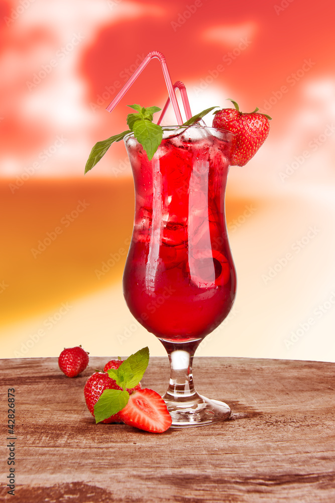 Strawberry cocktail in sunset with blur beach on background