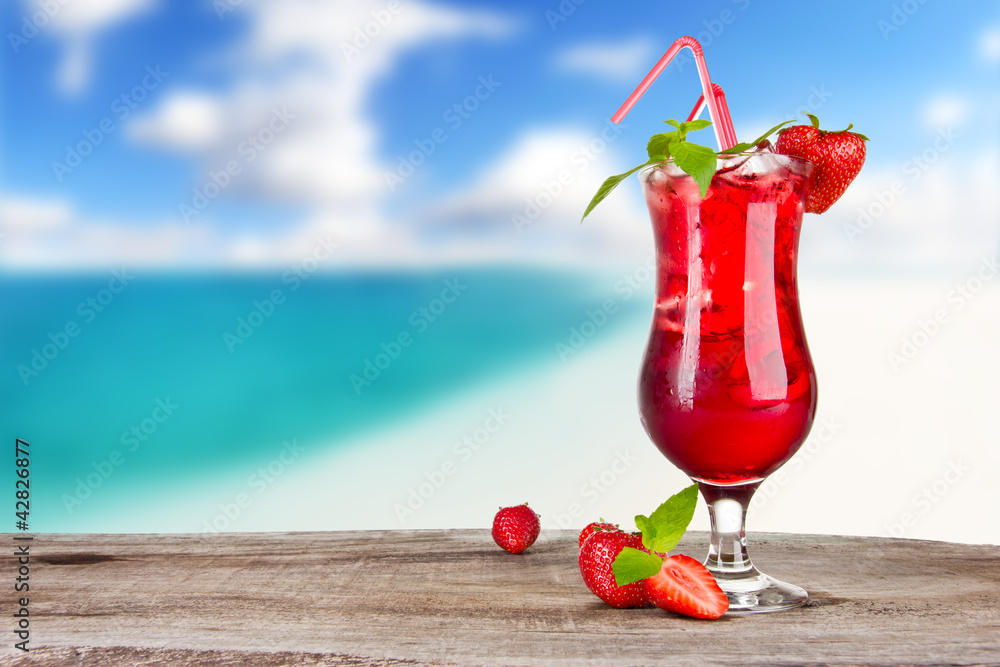 背景为模糊海滩的草莓鸡尾酒