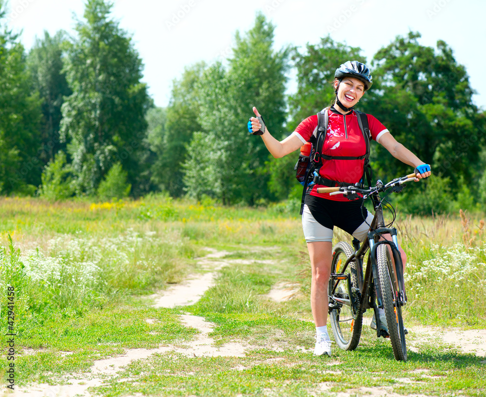 快乐的年轻女人在外面骑自行车。健康的生活方式