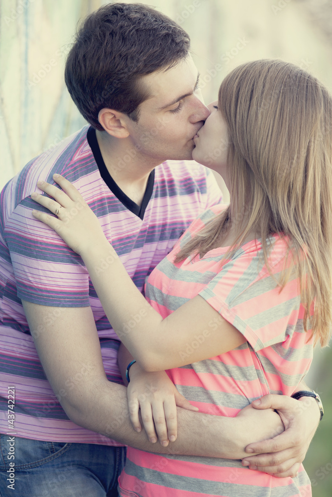 年轻情侣在涂鸦背景附近接吻。