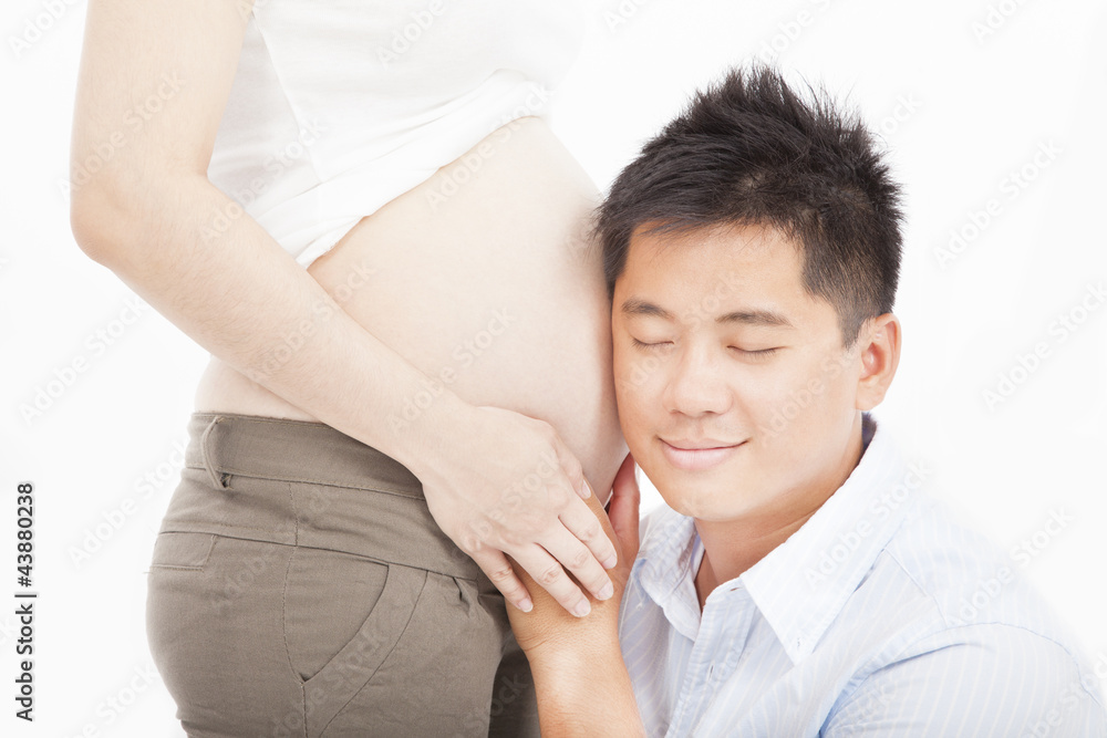 亚洲父亲在听她怀孕的妻子的肚子