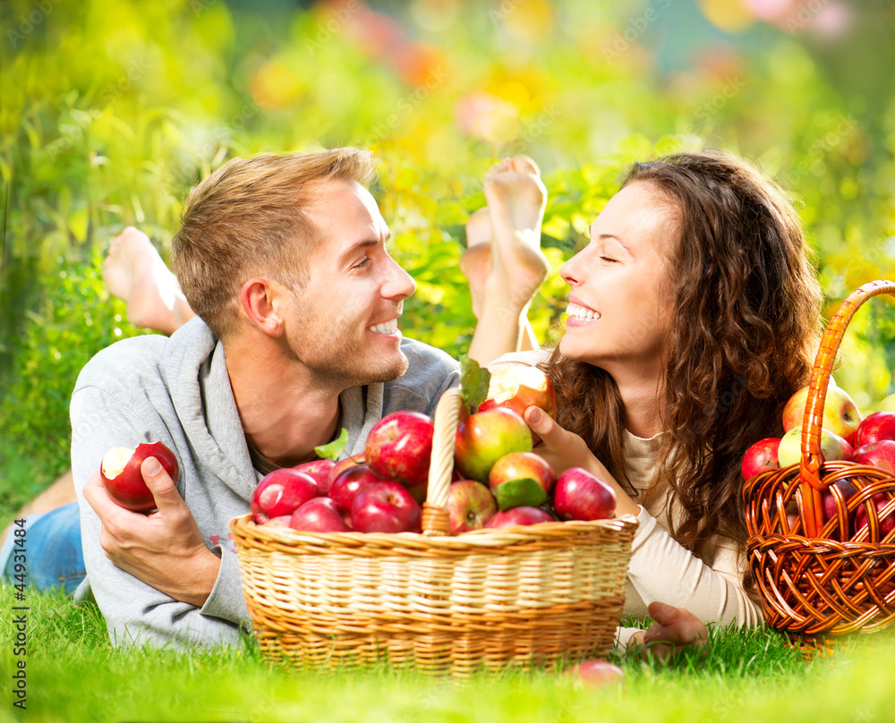 情侣在草地上放松，在秋园吃苹果