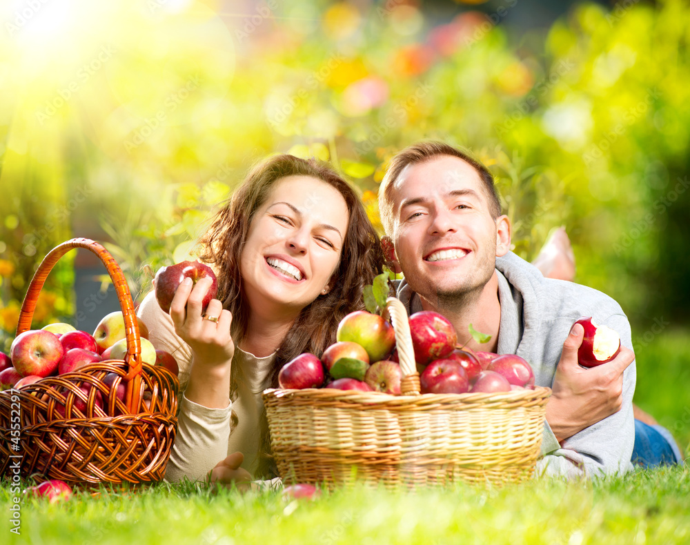 情侣在秋天的花园里吃草吃苹果