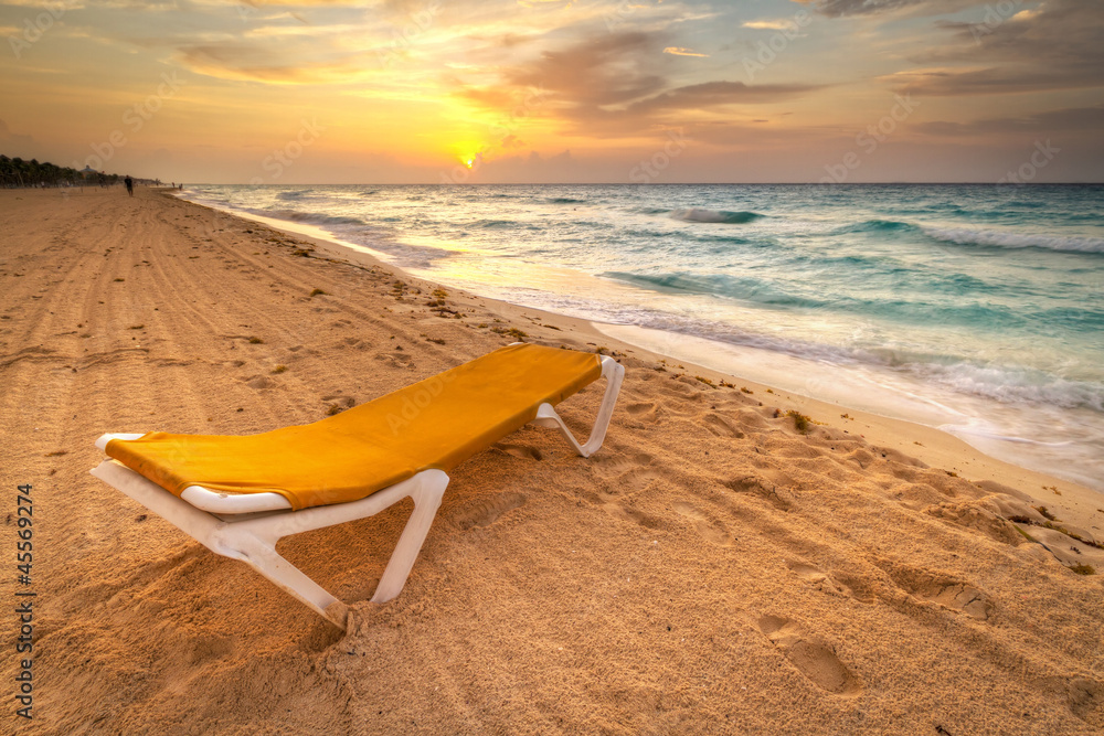 日出时加勒比海上的黄色躺椅
