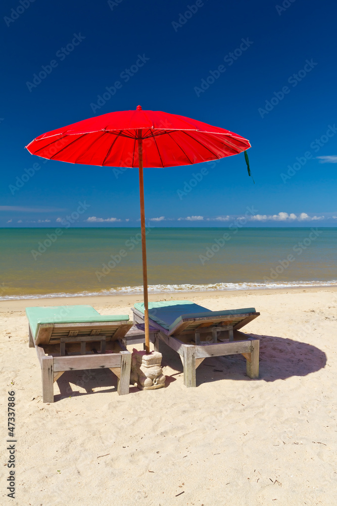 泰国热带海滩上带躺椅的红色遮阳伞