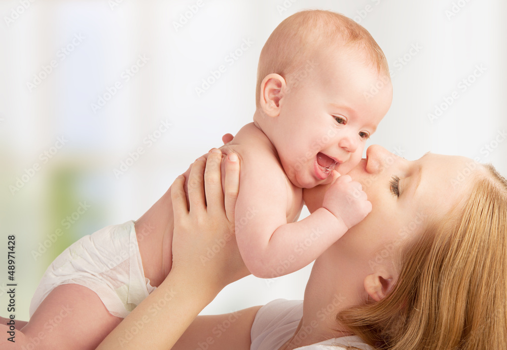 Happy  young mother kissing a baby