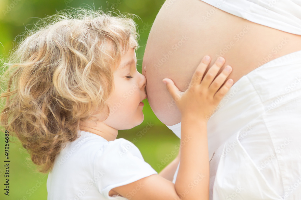 Child kissing belly of pregnant woman