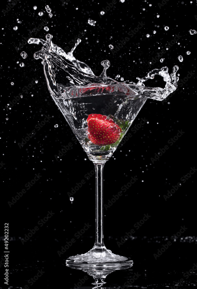 Martini drink splashing out of glass on black background