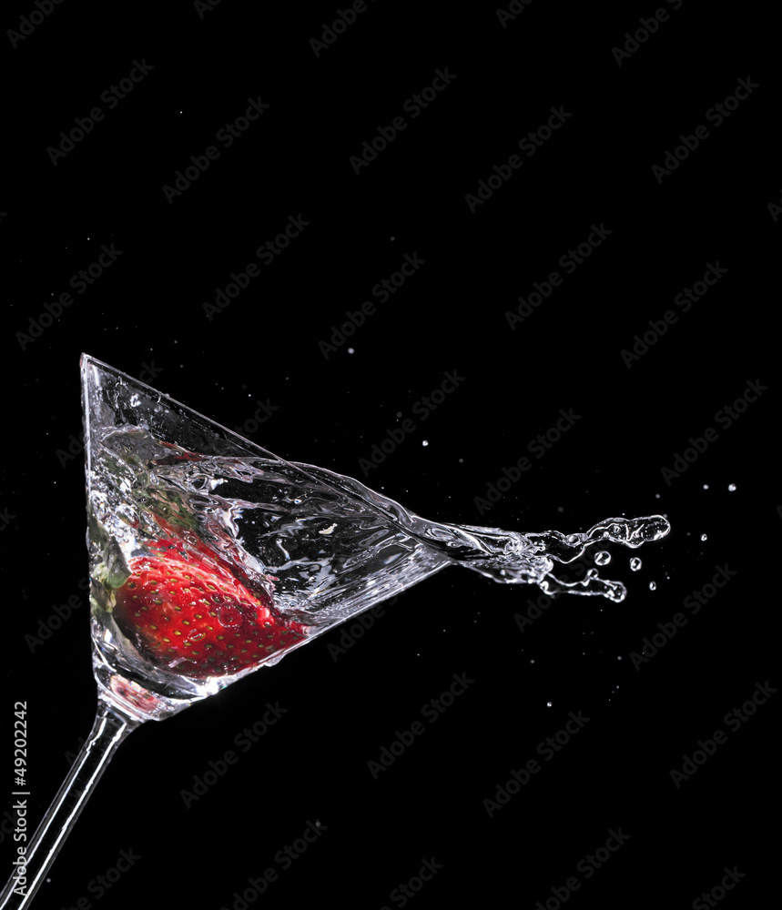 Martini drink splashing out of glass on black background