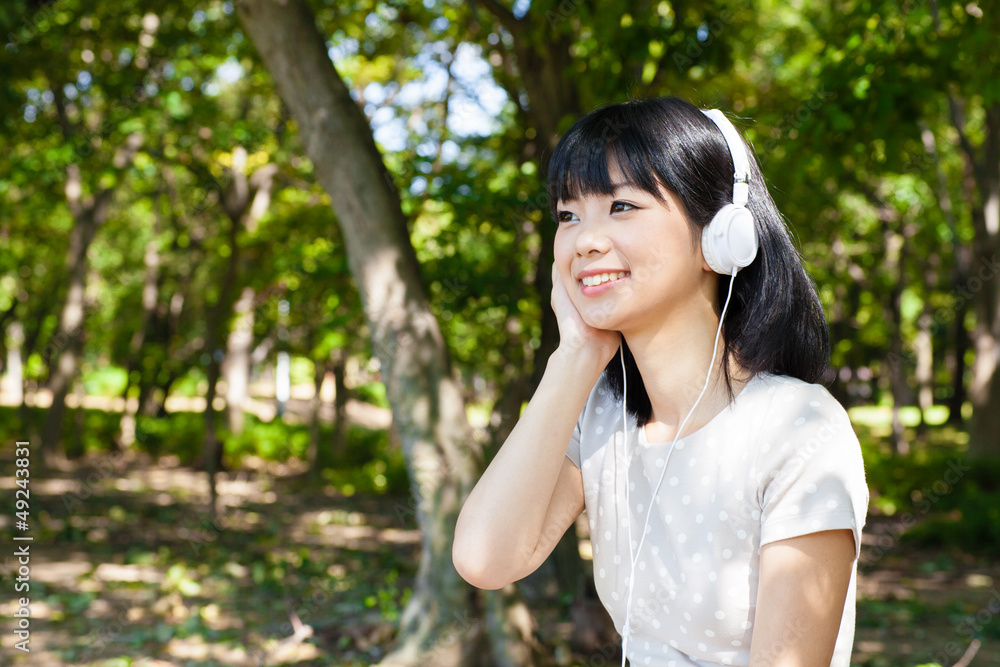 活跃的亚洲女人在公园里听音乐