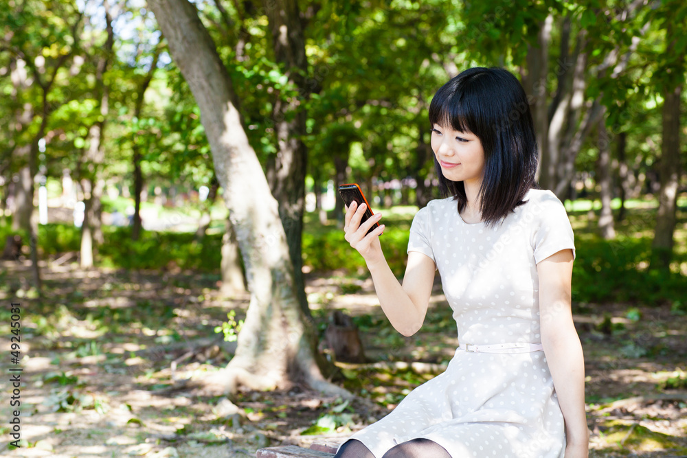 一名活跃的亚洲女子在公园里使用智能手机