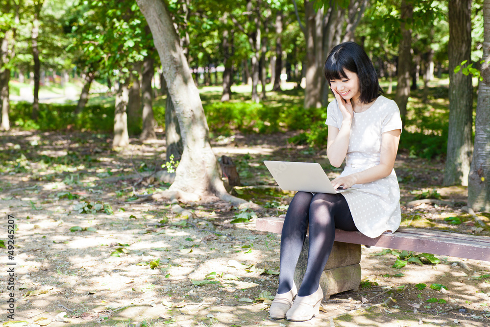 一个活跃的亚洲女人在公园里使用笔记本电脑