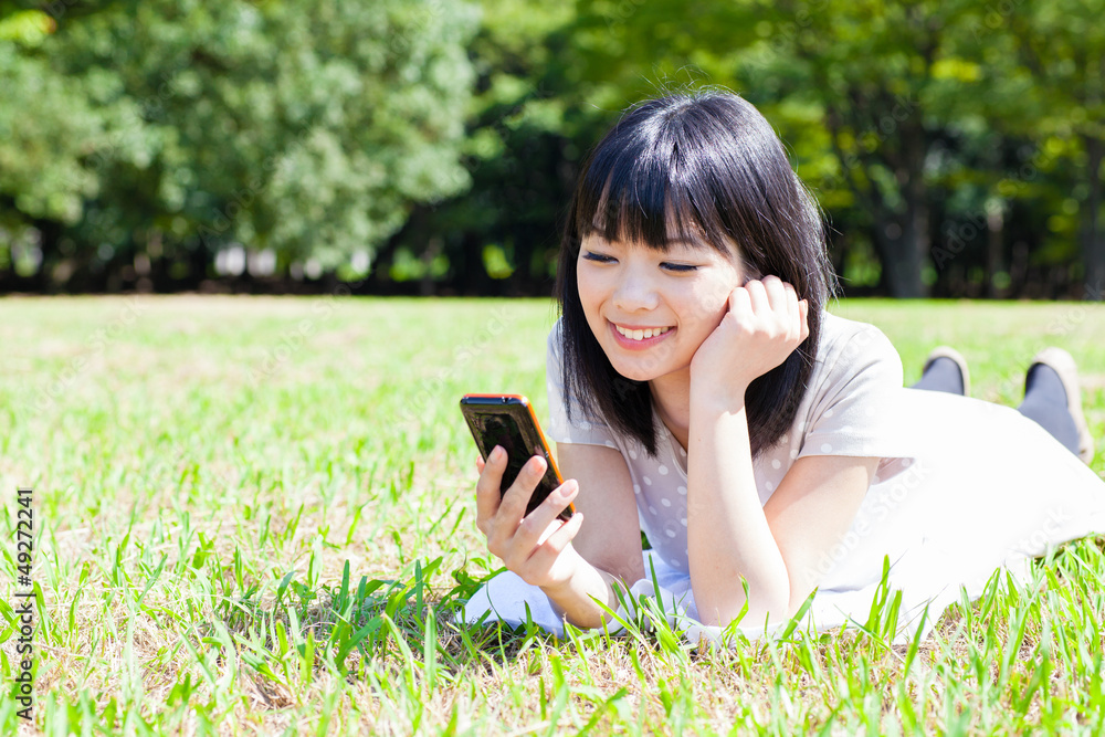 在公园里使用智能手机的亚洲美女