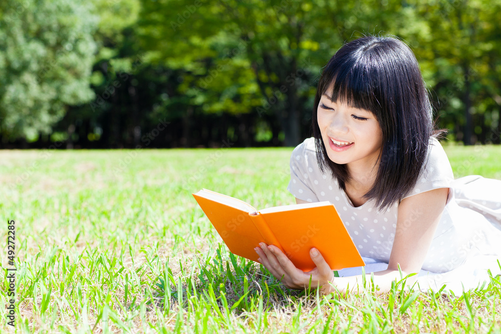 迷人的亚洲女人在公园看书