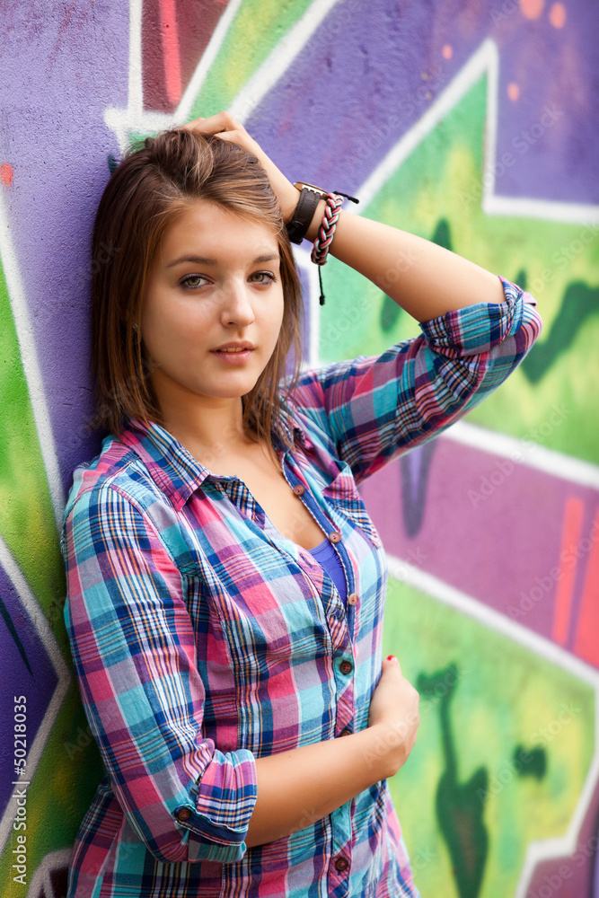 站在涂鸦墙附近的时尚少女。