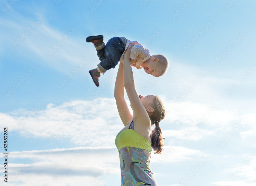 happy family. Mother throws up baby in the sky