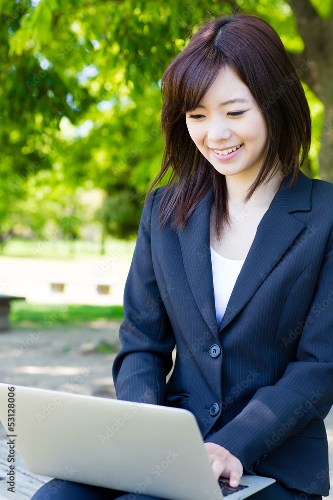 亚洲女商人在公园里使用笔记本电脑