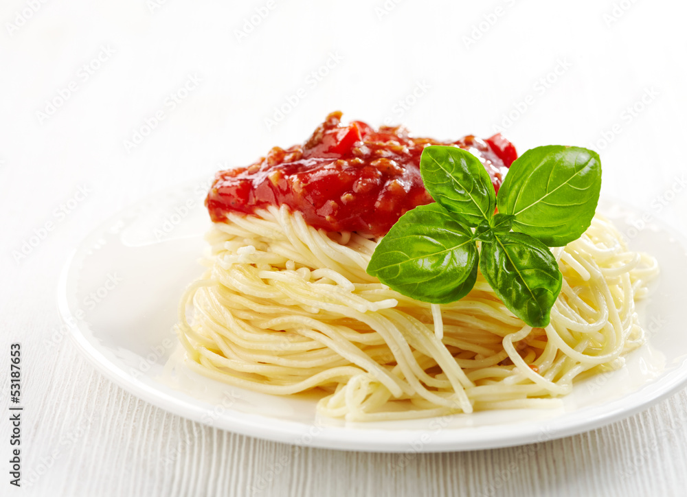 白盘子里的意大利肉酱面和绿色罗勒叶