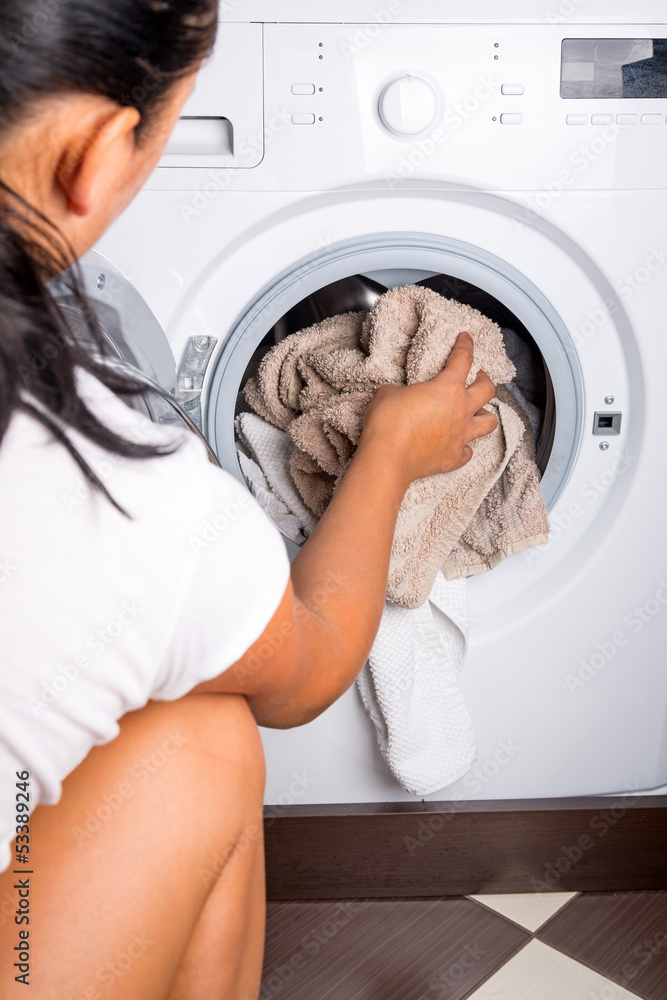 Woman loading laundry to the washing machine