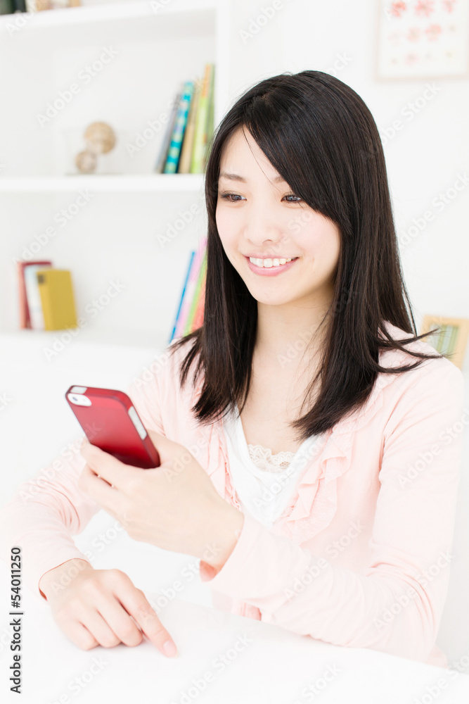 漂亮的亚洲女人在房间里使用智能手机