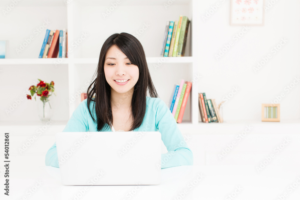 漂亮的亚洲女人在房间里用笔记本电脑
