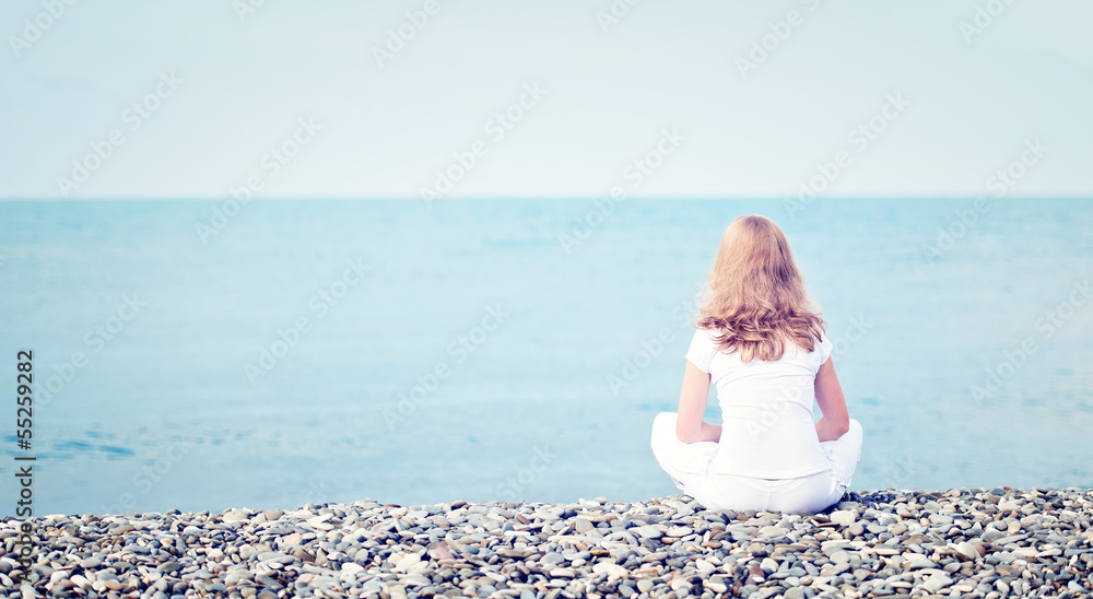悲伤孤独的年轻美女坐在海边的海滩上