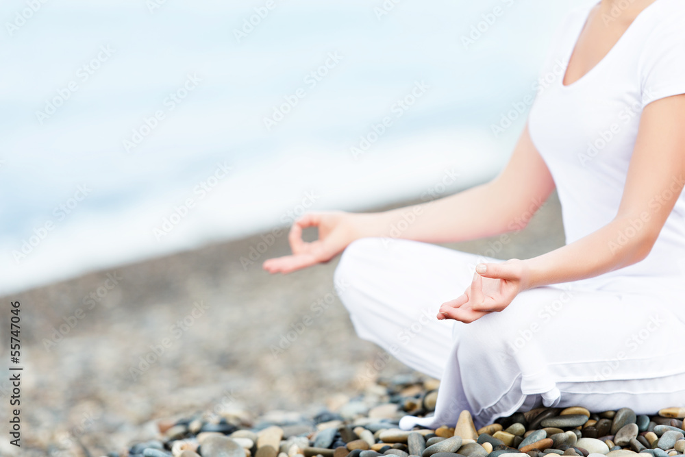 在海滩上以瑜伽姿势冥想的女人的手